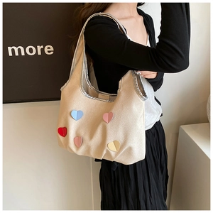 Détail du sac seau en PU beige avec cœurs 3D colorés et bordures passepoilées argentées