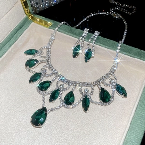 Macro view of emerald teardrop pendant necklace and earrings set in a velvet jewelry box