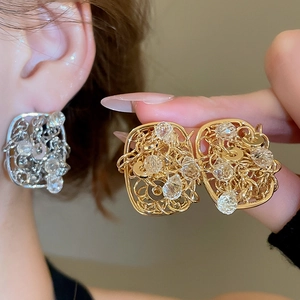 Detailed view of square hollow filigree earrings with gold and silver plating and crystals