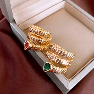 Macro detail of vintage gold snake rings with pear-cut red and green gemstones
