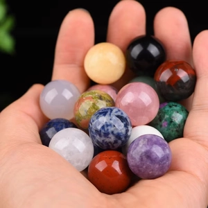 Variety of polished natural crystal spheres held in hand featuring multiple vibrant colors