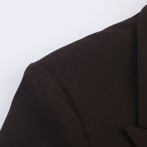 Gros plan du blazer marron foncé montrant le tissu sergé et la couture structurée de l'épaule
