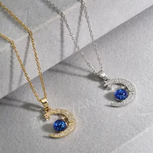 Gold and silver planet moon necklaces with blue stones on a grey stone staircase