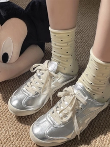 Vue détaillée de baskets en cuir argenté brillant portées avec style décontracté