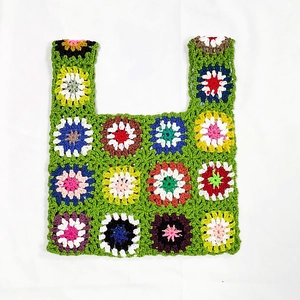 Detail of colorful hand-crocheted sunflower patterns on a green handmade tote bag
