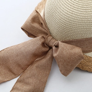 Detailed macro view of refined straw weaving and a stylish brown fabric bow on sun hat