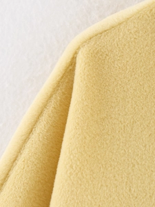 Macro view of bright yellow wool cape coat texture with detailed sewing craftsmanship