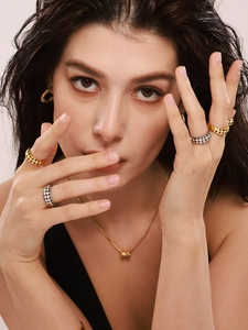 Close-up of black and white checkerboard enamel rings with gold necklaces on a model