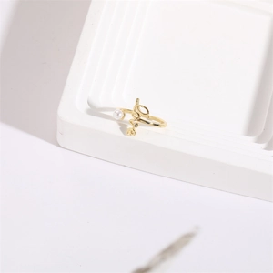 Minimalist gold open ring featuring a love script and pearl detail on white stand