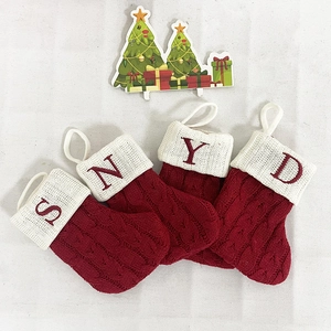 Detail of red knit Christmas stockings with embroidered letters S N Y D on white cuffs
