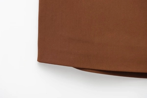 Gros plan détaillé du tissu en sergé marron caramel et des coutures de qualité de la jupe