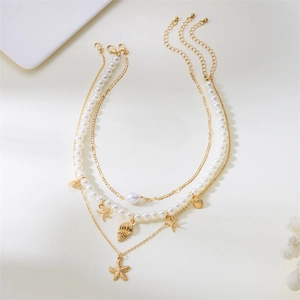 Close-up of layered gold necklaces with starfish, seashell pendants and baroque pearl