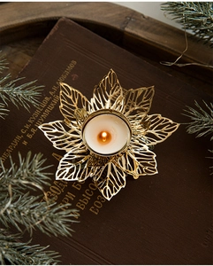 Golden leaf hollow metal candle holder on vintage book with festive pine needles
