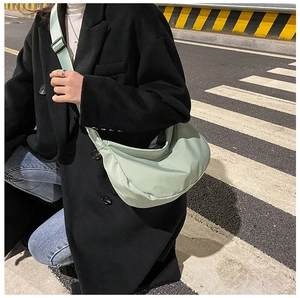 Detail of adjustable nylon strap and crossbody fit of the light green dumpling bag