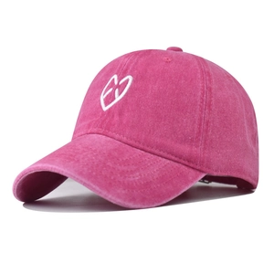Detail of washed pink cotton baseball cap featuring white heart and EXO embroidery