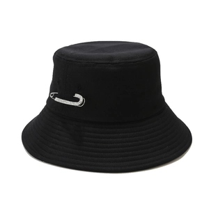 Wide brim black bucket hat with rhinestone safety pin accent on a solid white background