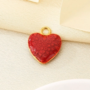 Macro detail of red enamel heart pendant with embossed textures and gold plating