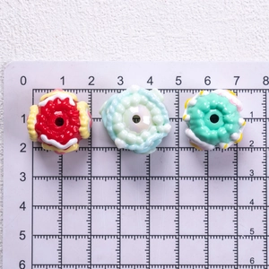 Detailed view of three 2cm hand-painted resin oil beads with unique patterns on a ruler