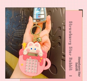 Detail view of a pink bunny cup mini calculator keychain with a golden bell and star charm