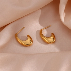 Polished gold-plated C-shaped drop earrings on elegant pink satin fabric background