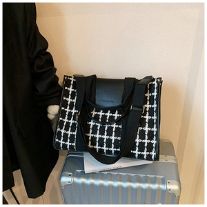 Detail of retro plaid tweed tote bag with PU leather flap on a silver suitcase