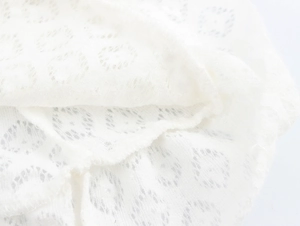 Close-up of white lace fabric detail showing hollow pattern and fine knit texture