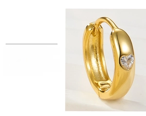 Detailed macro shot of gold plated heart shaped earring with white cubic zirconia inlay