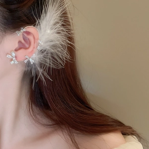 Close-up of a silver bow and white feather ear cuff with sparkling rhinestone accents