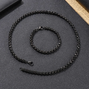 Detail of black box chain necklace and bracelet set with lobster clasps on textured background