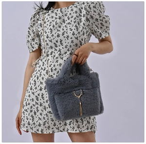 Detail of grey faux fur handbag with golden deer charm and elegant metal chain strap