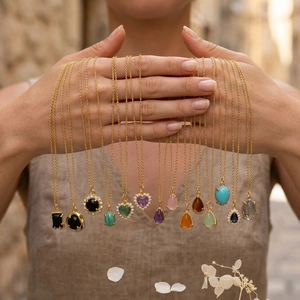 Detailed close-up of multiple heart and teardrop gemstone necklaces on 18K gold plated chains