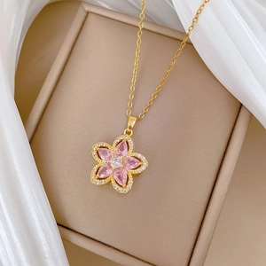 Detailed macro view of a gold flower pendant necklace with pink petals and crystal core