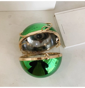 Dettaglio ravvicinato di una borsa da sera sferica in acrilico verde con manico dorato