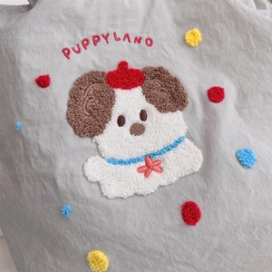 Detail of cute puppy embroidery and colorful dots on a grey canvas shoulder bag