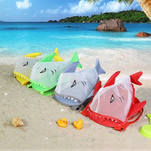 Colorful shark-shaped mesh beach bags for kids on sand with ocean background