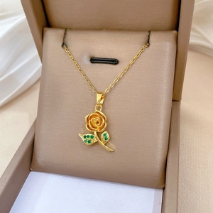 Detail of gold rose pendant with green zircon leaves inside a luxury jewelry box