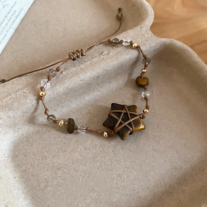 Close-up of star-shaped tiger eye stone and crystal beads on woven cord bracelet