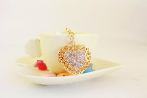 Detail of a sparkling crystal-studded gold heart keychain hanging on a small cup