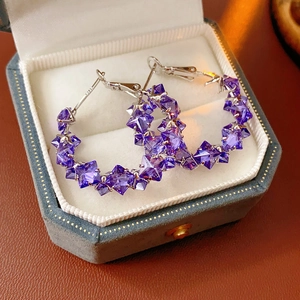 Close-up of S925 sterling silver earrings with purple star crystals in a jewelry box