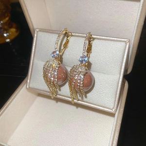 Macro detail of gold tassel earrings with blue zircon, diamonds and pink pearls in a box