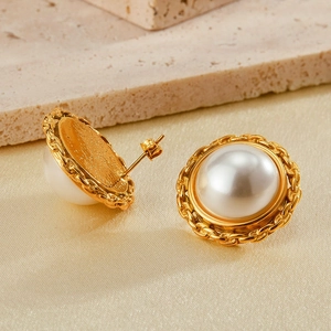 Detail of vintage gold plated earrings featuring large white pearls and woven chain borders