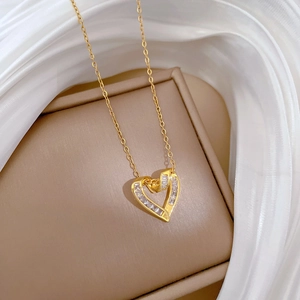 Detail of a gold heart pendant necklace with cubic zirconia on a luxury beige jewelry box