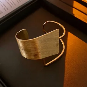 Minimalist open wide cuff bracelet with brushed gold finish and modern geometric design