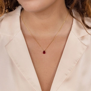 Gros plan d'un collier avec pendentif goutte en pierre rouge porté par un mannequin