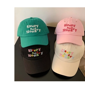 Detail shot of cotton baseball caps in green, pink, black and beige with letter embroidery