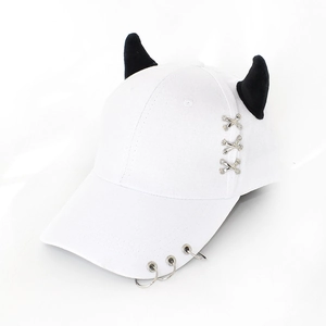 Detail of white baseball cap featuring black devil horns and silver metal ring accents