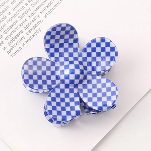 Detailed view of a blue and white checkered flower claw clip on an open book