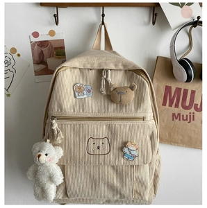 Detalle de mochila de pana con bordado de oso y llavero de oso de peluche suave
