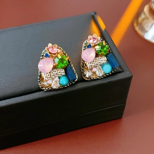 Close-up of vintage geometric triangle earrings with colorful crystals on a black stand