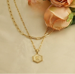Detailed close-up of 18K gold stainless steel paperclip chain with letter E pendant